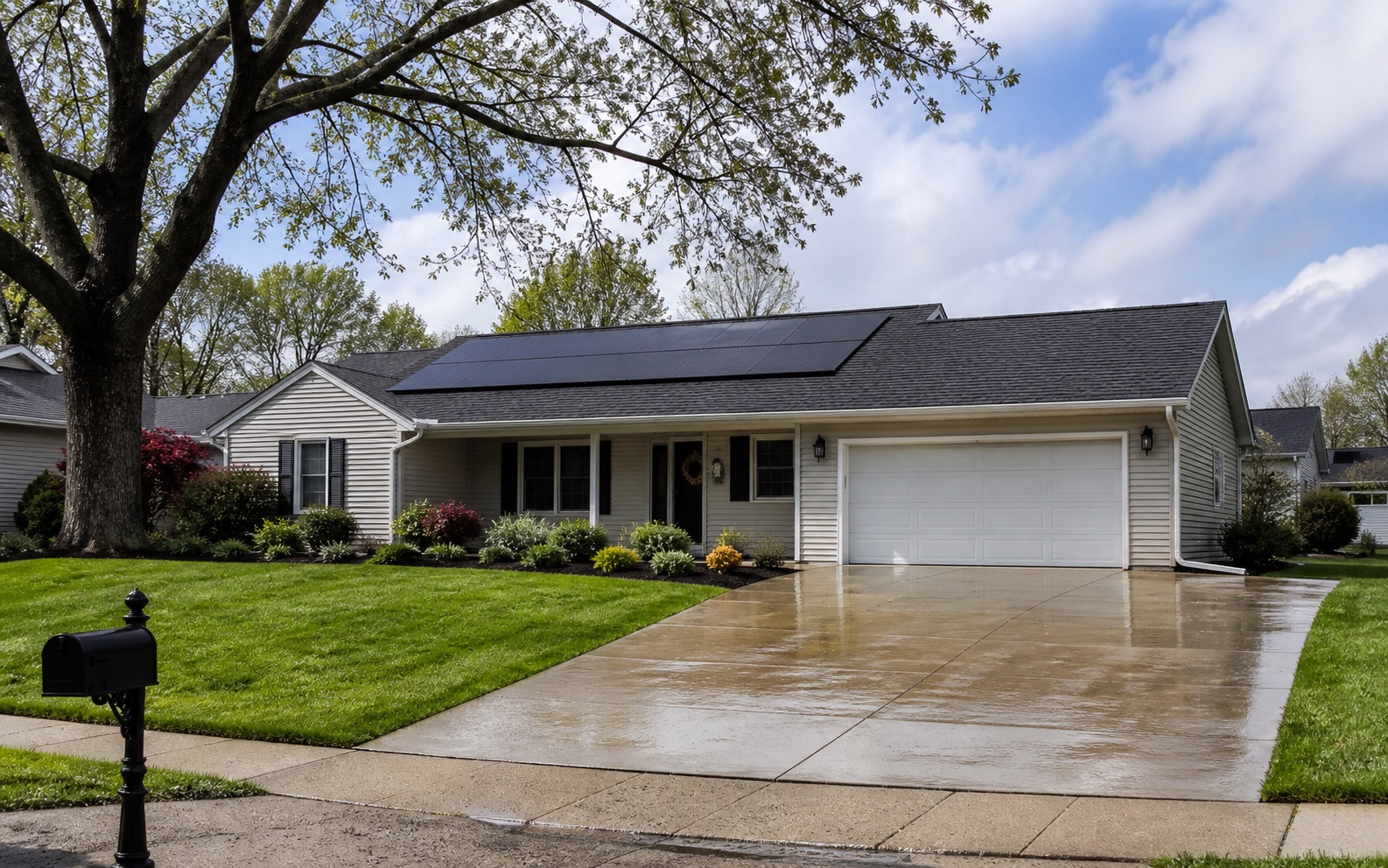 Ranch home with rooftop solar panels and a rain-wet driveway in an Illinois neighborhood