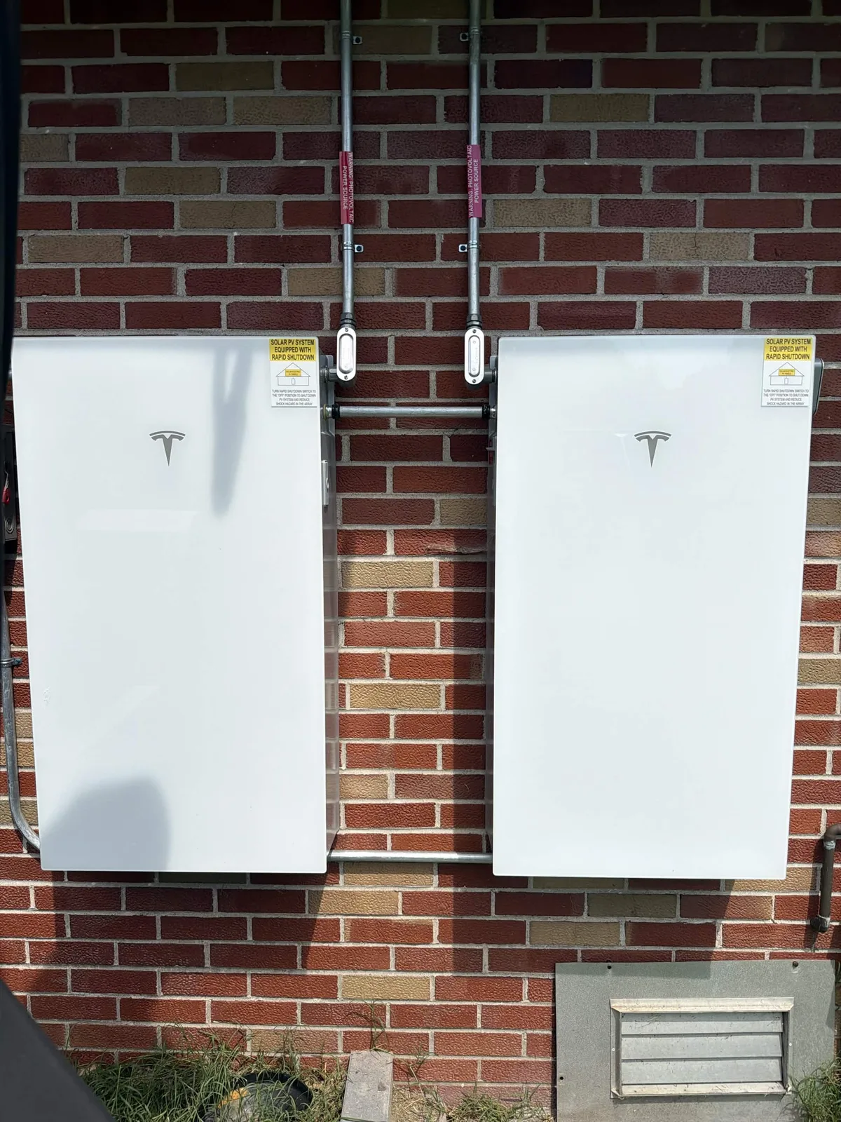 Two Tesla Powerwall batteries installed side by side on a brick wall of an Illinois home