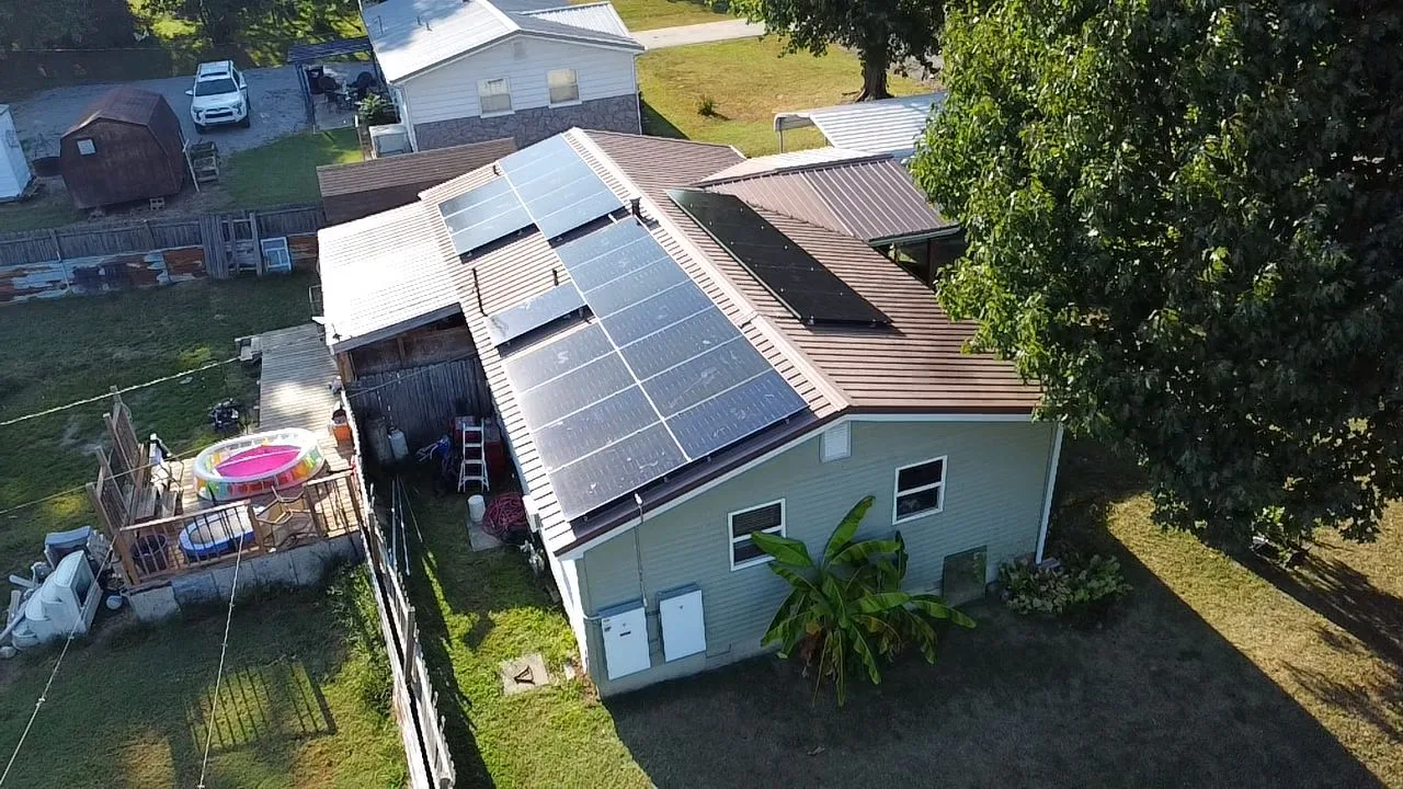 Oblique drone view of solar panels across the brown metal roof of a rural Illinois home