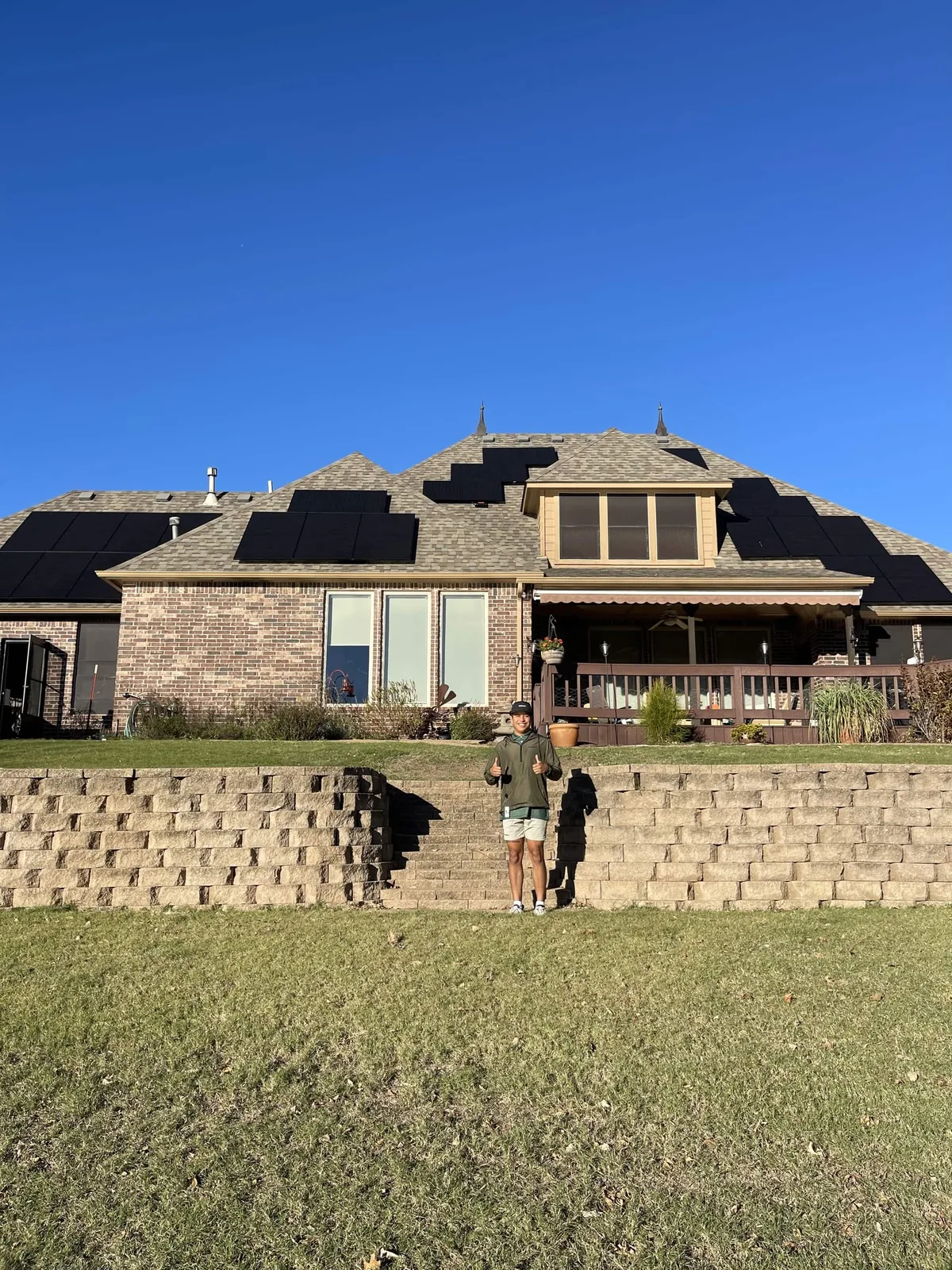 The same brick ranch home after going solar with Direct Solar Pros, black panels across the roof